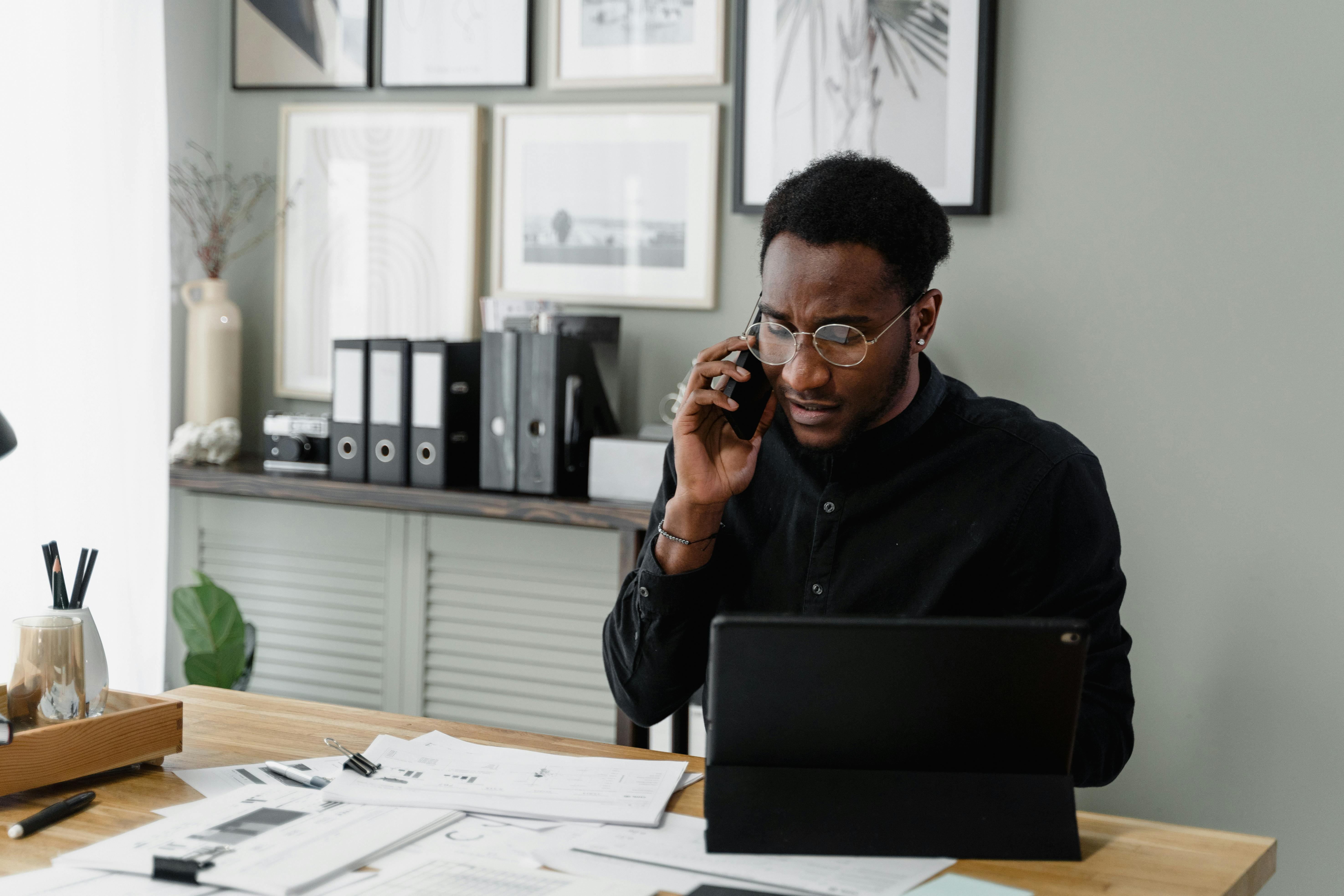 business man on cell phone with papers on his desk