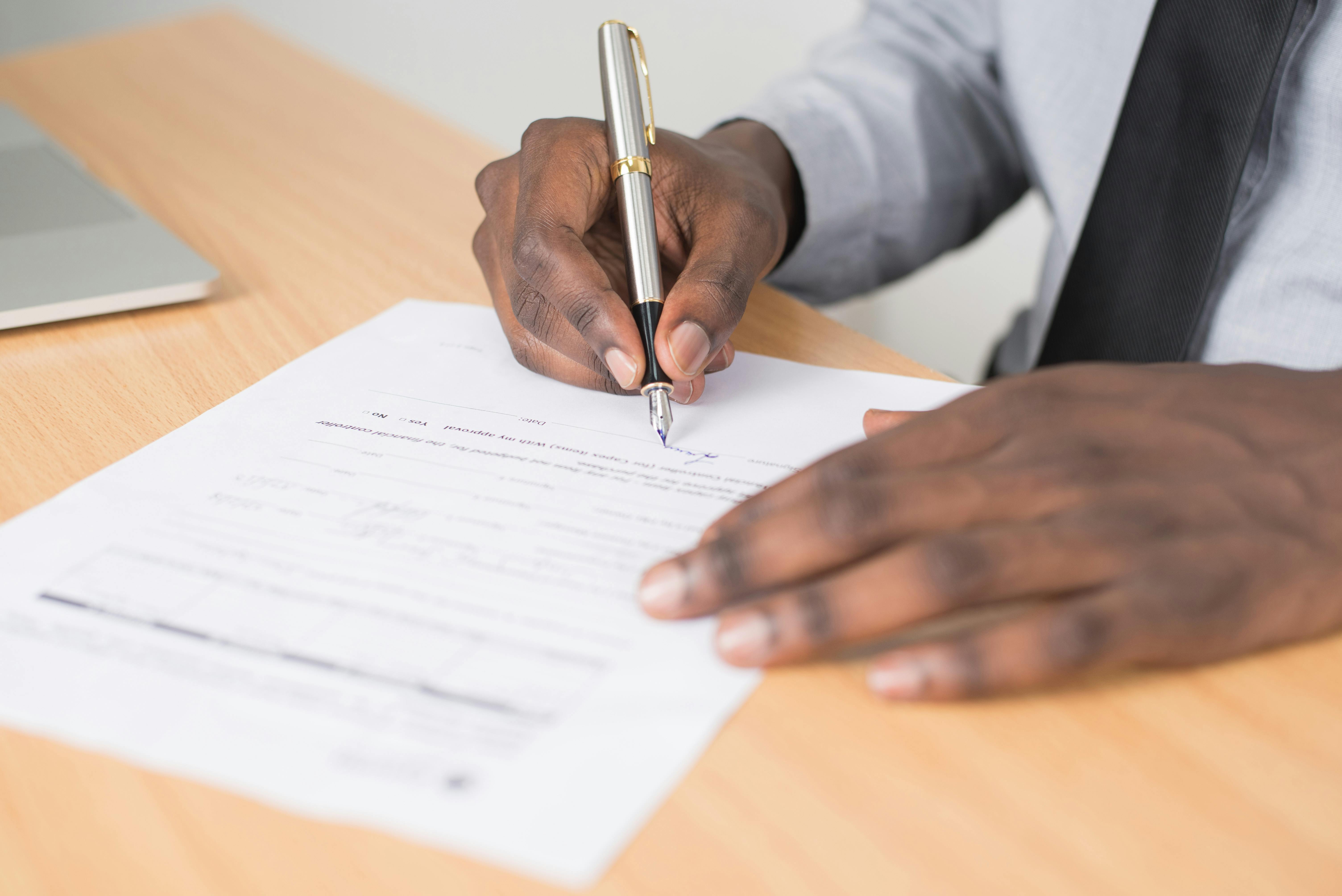 Person signing document with pen